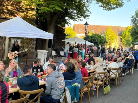 Menschen an langen Tischen in der Einkaufszone