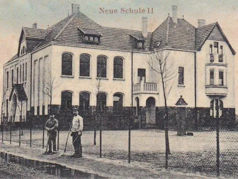 Zwei Männer vor einem großen Schulgebäude