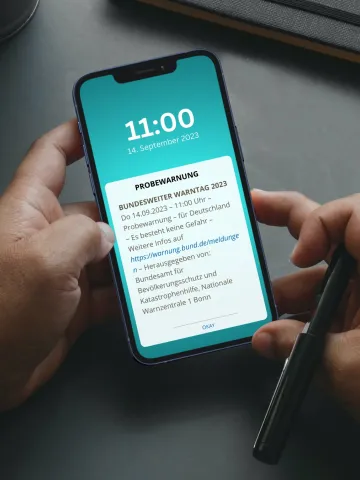Hände halten Smartphone mit Probealarmanzeige 
