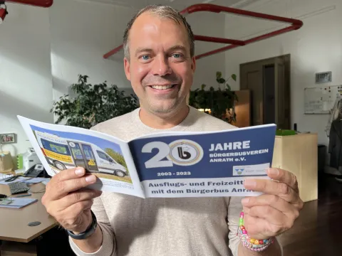 BM hinter der  Broschüre 20 Jahre Bürgerbus Anrath 