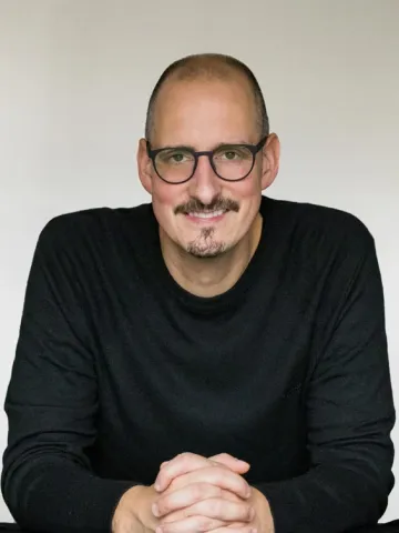 Der Autor Andreas Lattke blickt lächelnd in die Kamera